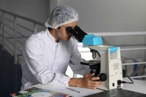 PhD student using white microscope