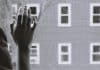 A lonely hand on a window pain while it rains outside