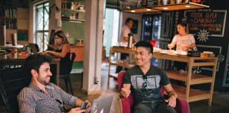 Friends chatting indoors while sitting in armchairs