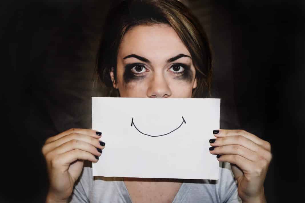 A crying person holding a smile over their mouth