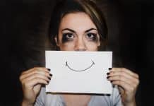 A crying person holding a smile over their mouth