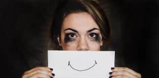 A crying person holding a smile over their mouth