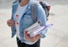 A woman clutches folders and books