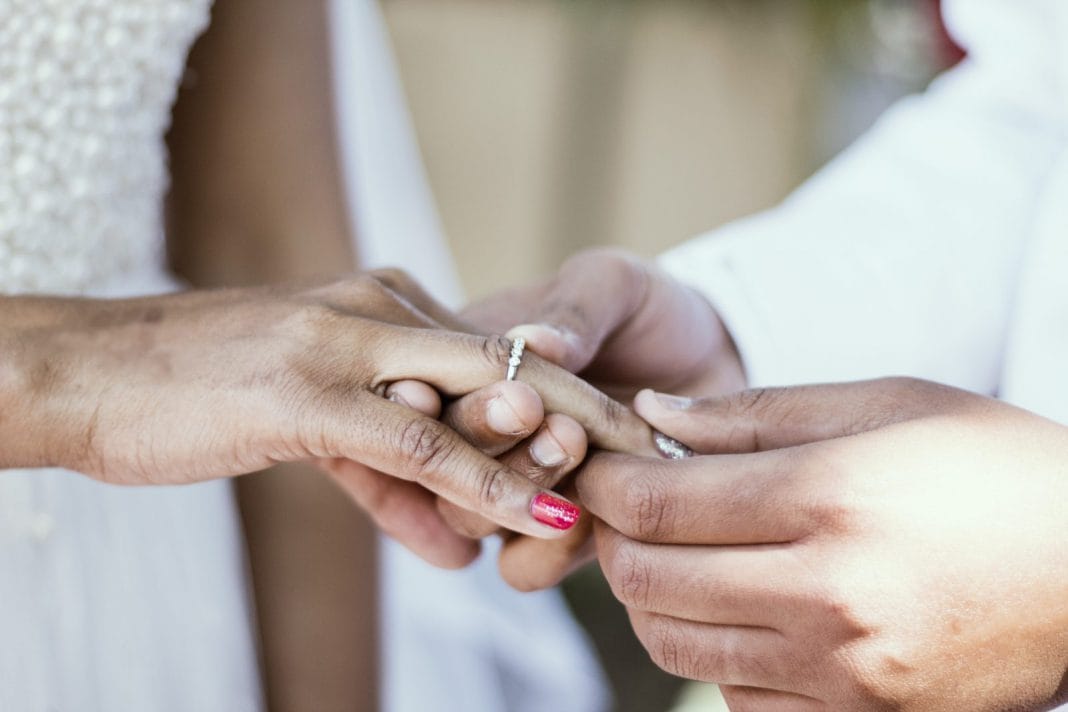 A hand puts a wedding ring on someone's ring finger