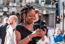 A young black woman smiles at her phone