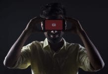 A man holds up a phone with YouTube on it.
