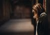 A young woman looks down in a dark alleyway