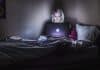 A woman working on a Macbook in the dark