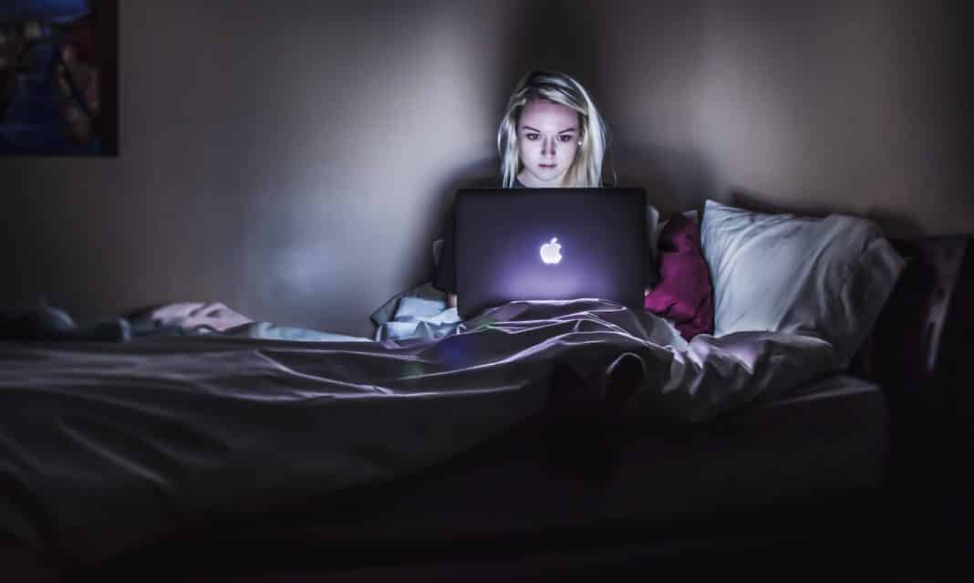 A woman working on a Macbook in the dark