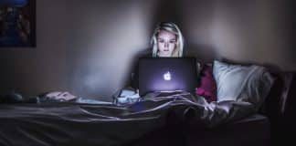A woman working on a Macbook in the dark