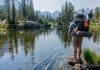 A person with a backpack standing by a lake