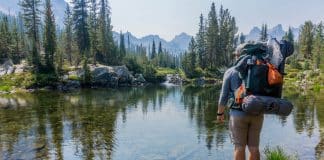 A person with a backpack standing by a lake