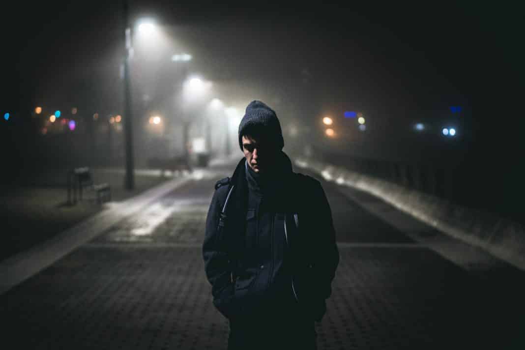 A man walking along a dark road at night