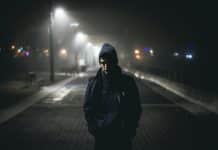 A man walking along a dark road at night