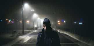 A man walking along a dark road at night