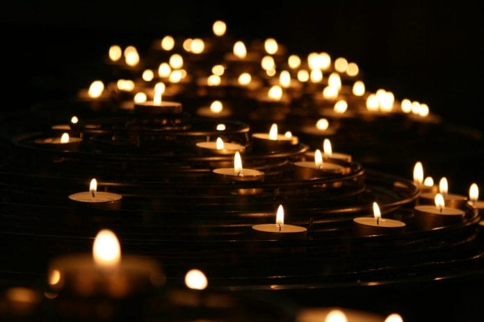 A series of lit tealights in the darkness