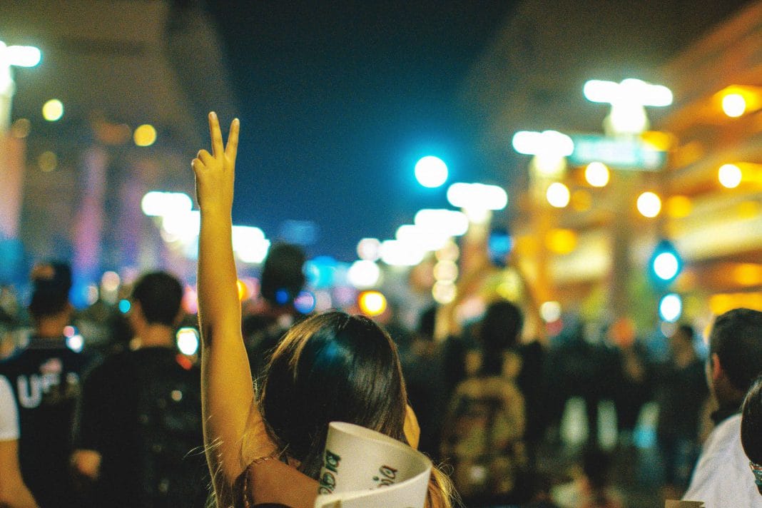 A protester makes a V symbol above her head