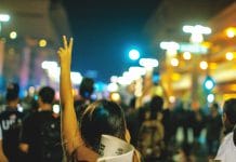 A protester makes a V symbol above her head