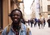 A young black man standing in the street and smiling