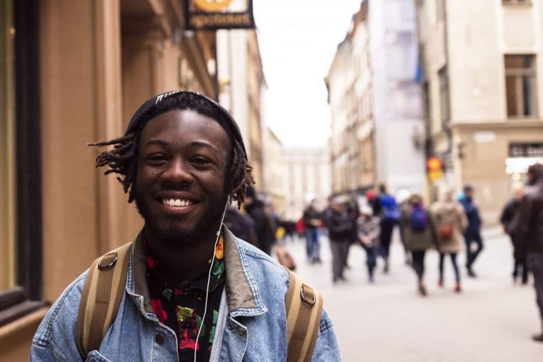 A young black man standing in the street and smiling