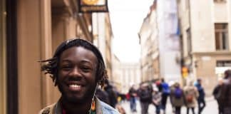 A young black man standing in the street and smiling