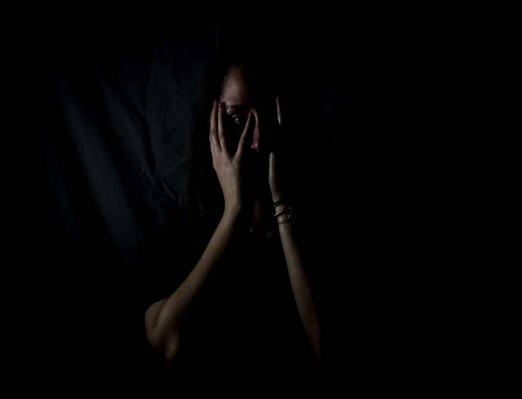 A woman holds her hands up to her face in fear