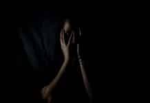 A woman holds her hands up to her face in fear