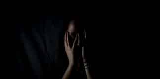 A woman holds her hands up to her face in fear