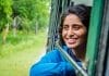 An Indian girl smiles while looking out the window of a vehicle