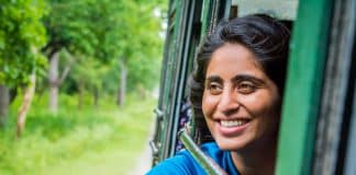 An Indian girl smiles while looking out the window of a vehicle