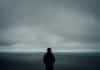 A person standing alone in front of a grey sky