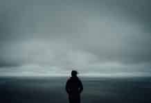 A person standing alone in front of a grey sky