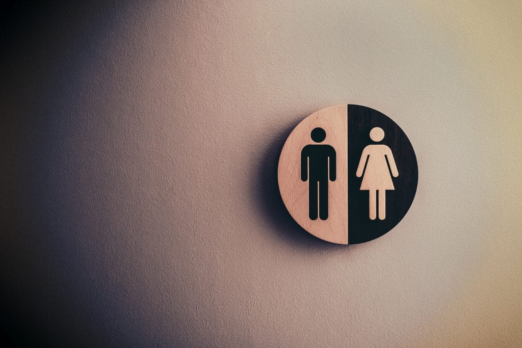 A circular sign showing a male outline on the left and a female outline on the right.