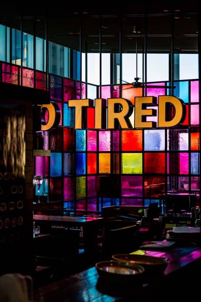 A sign saying 'Tired' in front of coloured windows