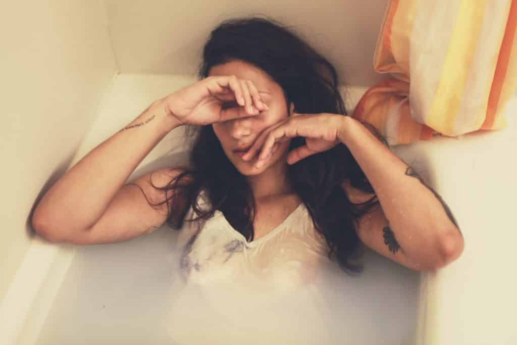 A woman looks distressed in a bathtub