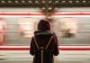 A young woman stands by a passing metro train