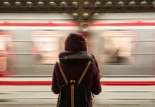 A young woman stands by a passing metro train