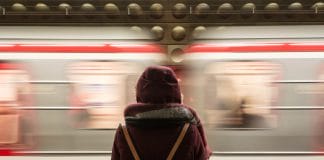 A young woman stands by a passing metro train