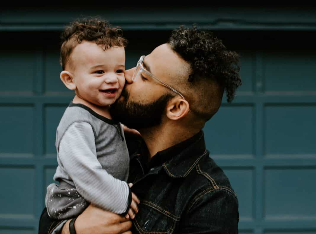 A father kisses his young child on the cheek