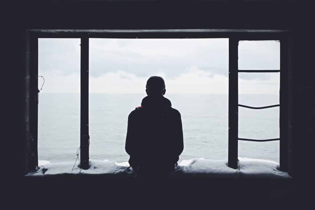 A man sits on a window ledge