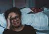 A woman cries, sitting by her bed