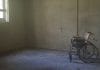 An empty wheelchair in a tatty room