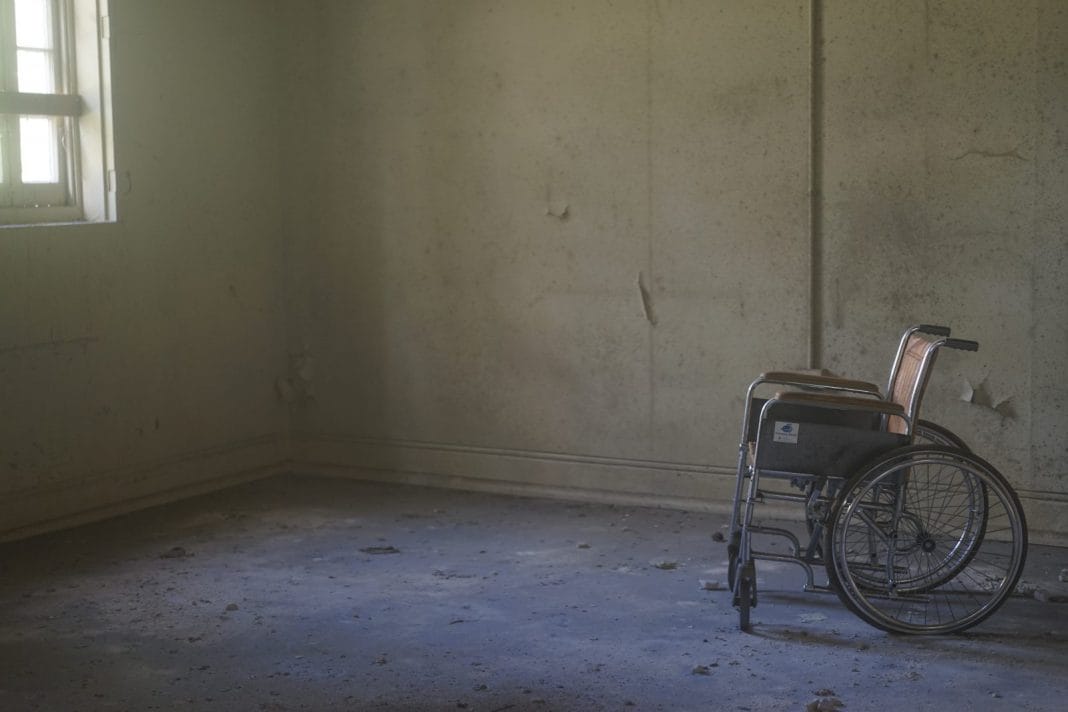 An empty wheelchair in a tatty room