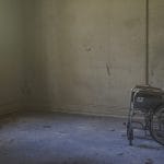 An empty wheelchair in a tatty room
