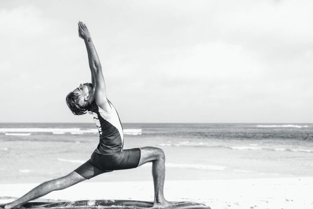 A man does yoga on the beach