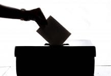 A hand puts a voting slip into a ballot box