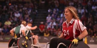 A smiling young woman in a wheelchair plays wheelchair basketball