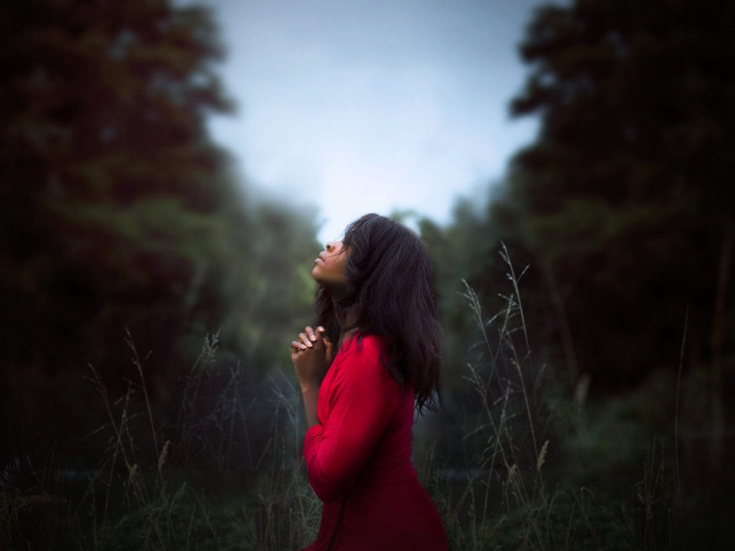 A young woman in a red dress prays