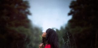 A young woman in a red dress prays