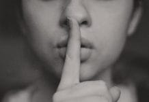 A black and white image of a woman with a finger over her lips